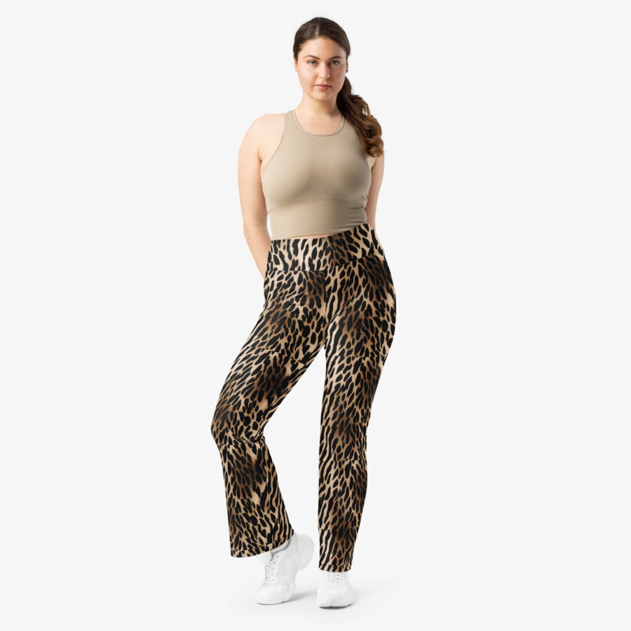 Woman posing front-facing in Wild Charm Leopard Flare Leggings with hands in pockets, styled with a beige sleeveless top and white sneakers.