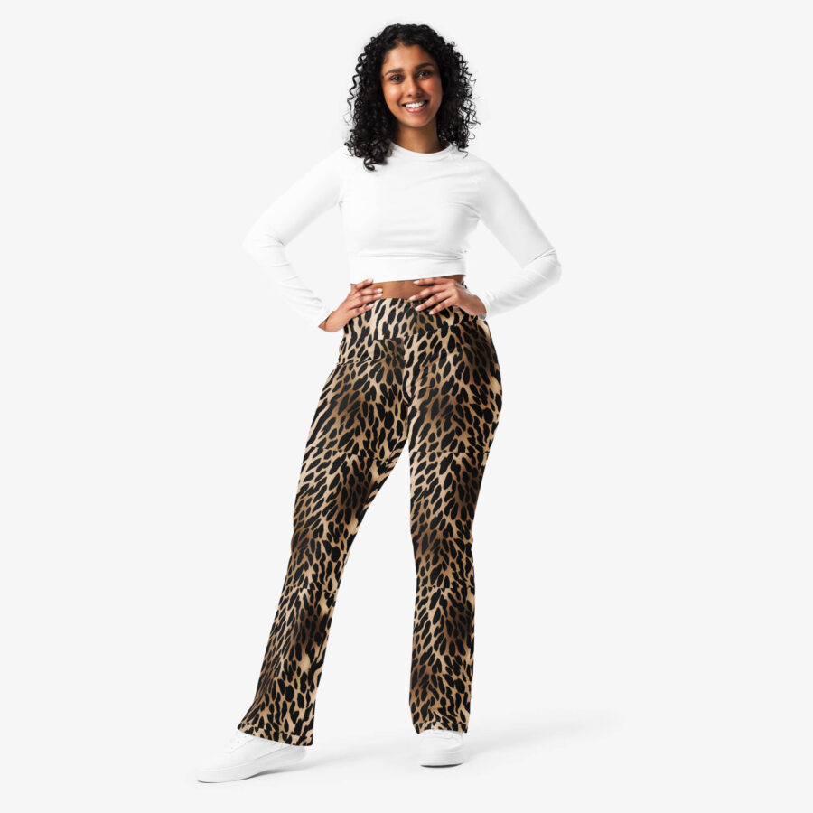 Smiling woman wearing Wild Charm Leopard Flare Leggings and a long-sleeve white crop top, hands on hips, styled with white sneakers.