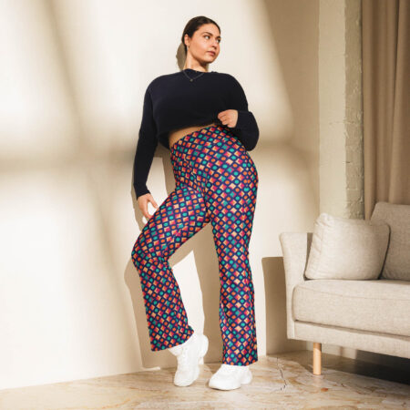 Woman posing in sunlight next to a couch wearing Electric Geo Flare Leggings and a black crop sweatshirt, showcasing the flared bottom and bold print.