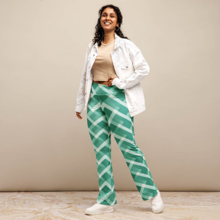 A smiling woman stands confidently in a beige top and white jacket, wearing emerald grid flare leggings with bold geometric lines.