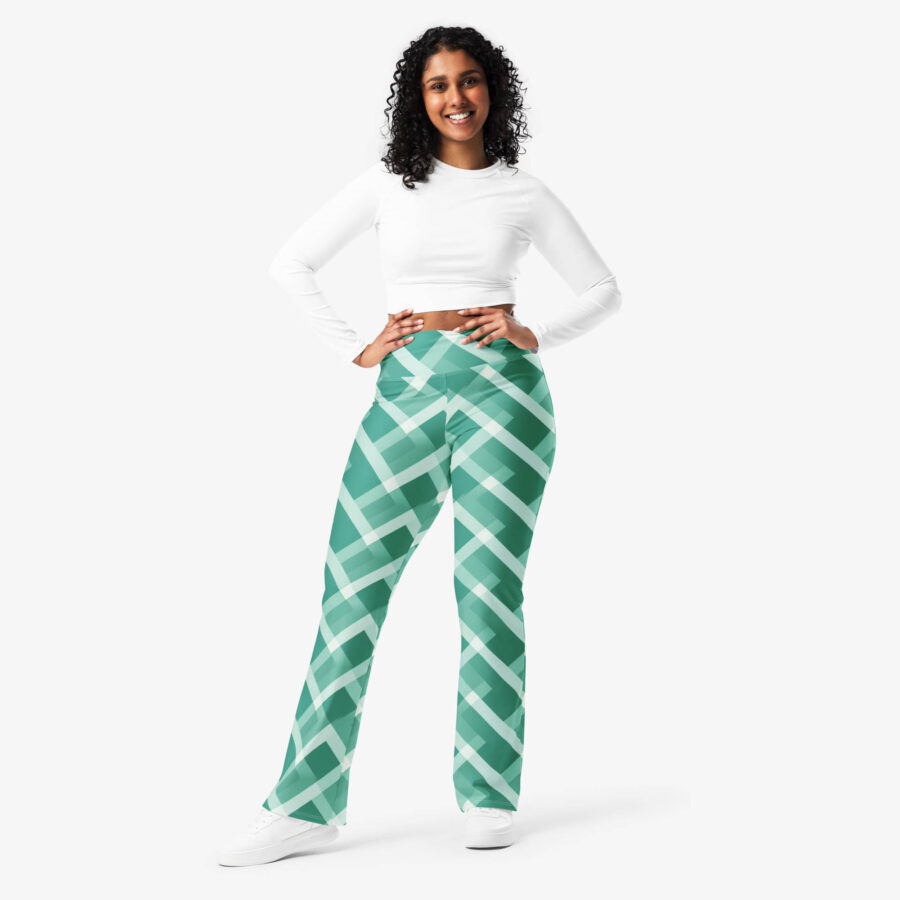 Woman poses with hands on hips wearing emerald green and white criss-cross flare leggings and a fitted white long sleeve crop top.