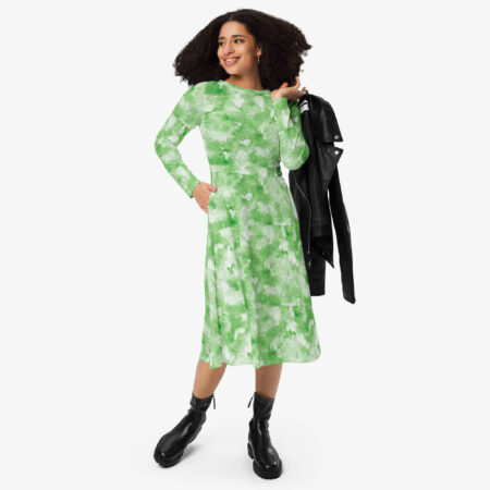 Woman wearing a green and white cloud-print midi dress, styled with black boots and a black leather jacket in hand.