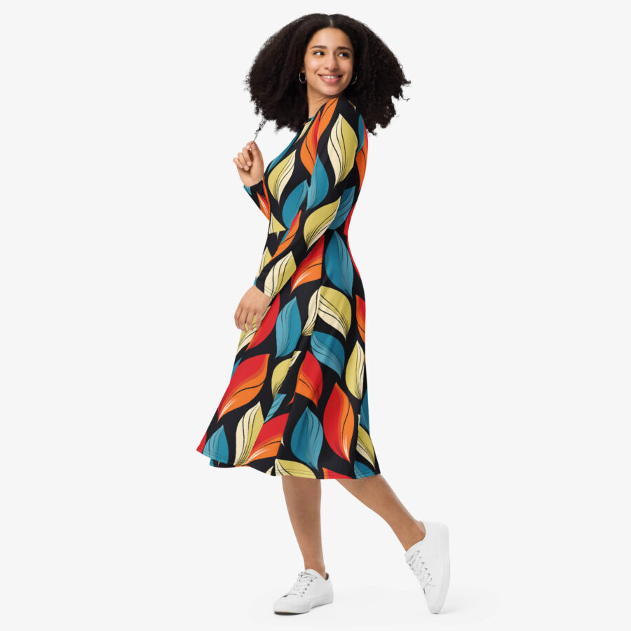 Side view of a woman walking in the Harvest Drift Midi Dress, highlighting the flowing midi cut and colorful leaf motif against a dark base.