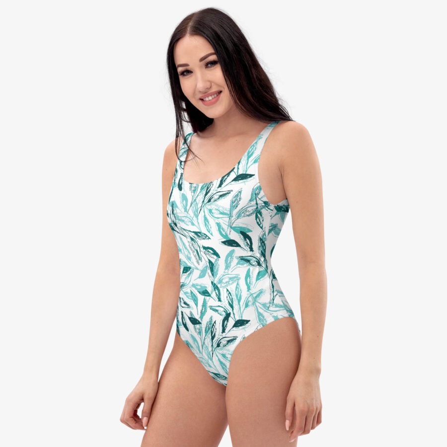 Smiling model wearing the Botanical Harmony One Piece Swimsuit, showing the scoop neckline and vibrant green leaf print from the front.