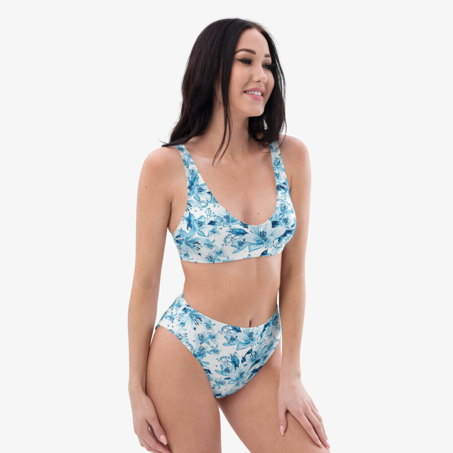 Front view of a woman smiling in the Azure Bloom High Waisted Bikini with a scooped neckline and vivid blue floral print on a clean white base.