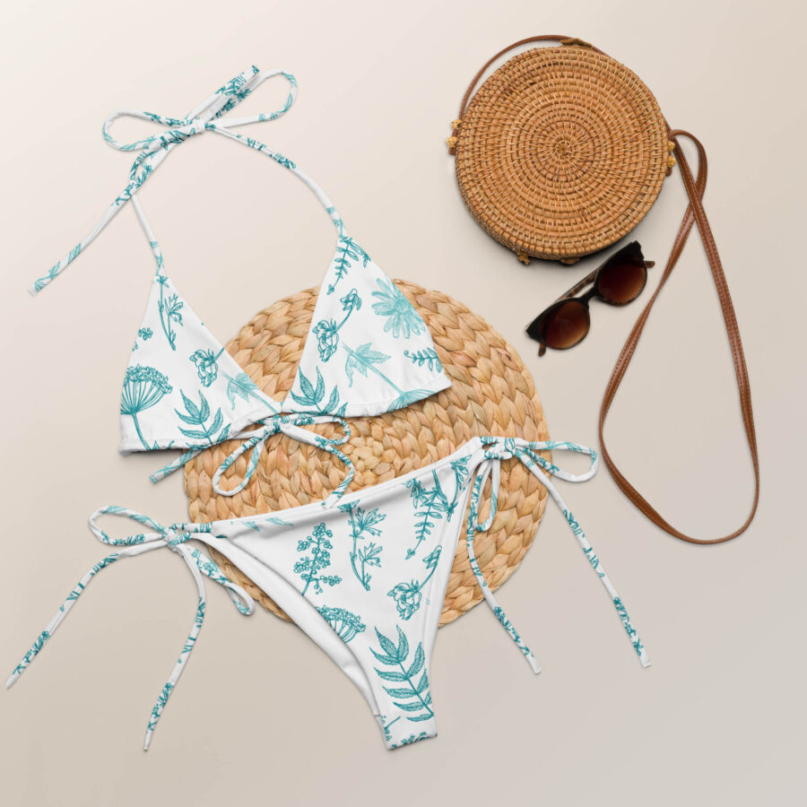 Flat lay of the Botanical Harmony String Bikini set displayed with summer accessories including a straw bag and sunglasses.