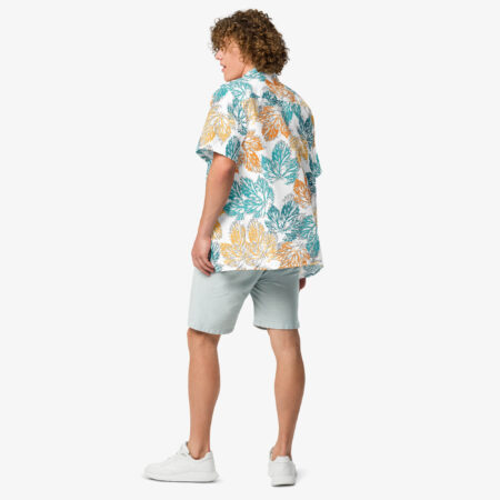 Male model wearing the Autumn Mirage Button Shirt with light shorts and white sneakers, turned slightly to show the relaxed fit and bold leaf pattern from the back.
